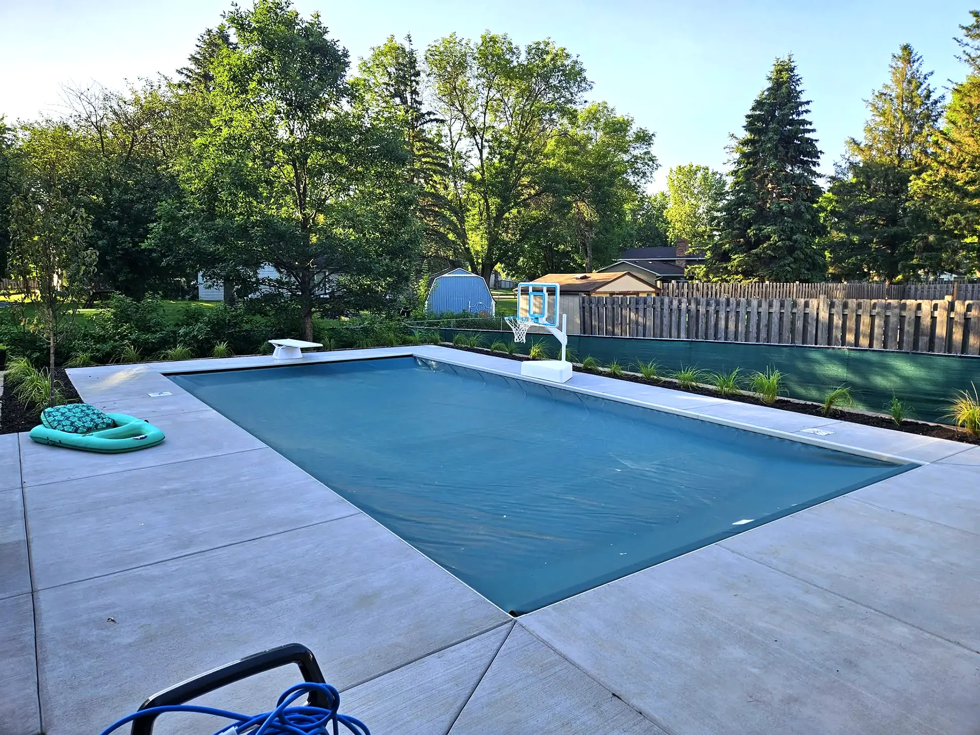 Backyard swimming pool covered with a fitted automatic pool cover in Maple Grove, MN.